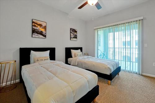 奥兰多Loftly Luxury Modern Oasis 2BR 2BA apartment Windermere FL, near Disney, Universal Studios, Magic Kingdom, Pool, Gym, Patio, free cable, wifi, free parking, gym, Alexa, lake, gated community, spacious closets, close to shops and mall的一间卧室设有两张床和大窗户