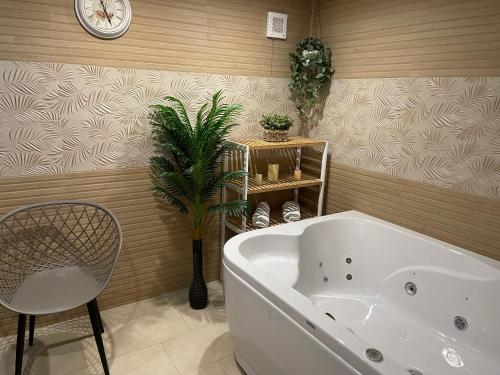 西格伏沙尔克Paradise SPA Hotel的带浴缸、植物和时钟的浴室