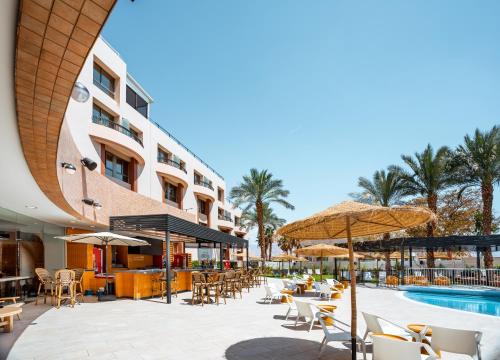 埃拉特Jacob Eilat的酒店庭院设有桌椅和游泳池