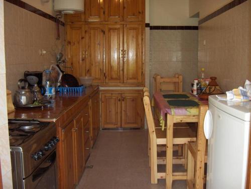 马拉喀什Villa Romancia Ourika Vallee的厨房配有木制橱柜、桌子和炉灶。