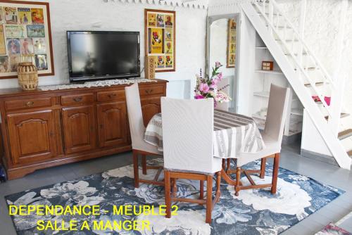 Saint-Vincent-SterlangesChez Martine et Bernard的一间带电视和桌椅的用餐室