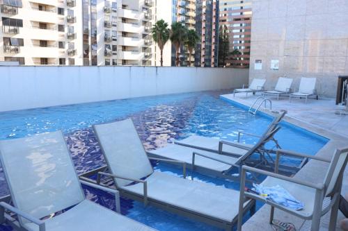 巴西利亚Flat Premium Particular Cullinan Hotel的一组椅子坐在游泳池里