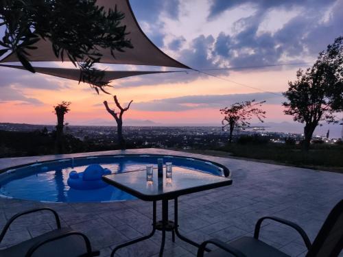帕萨里迪Yiorgos, amazing sunset view house的一个带桌椅的游泳池,享有日落美景