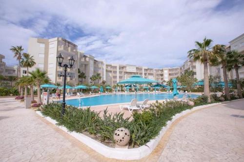 莫纳斯提尔2 Bedrooms apartment swimming pool的一个带椅子和遮阳伞及棕榈树的度假游泳池