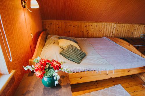 IeriķiBrīvdienu māja ar pirti "Strautkalni"的花瓶里花的木房里的一个床