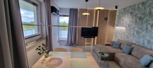 苏瓦乌基62m2 Apartament PREMIUM Łąki i Pola, ELEKTRYCZNE ROLETY, KLIMATYZACJA, GARAŻ, ŁADOWARKA AUT ELEKTRYCZNYCH的客厅配有沙发和桌子