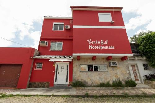 里奥格兰德Hotel Pousada Vento Sul的红色的建筑,上面有标志,上面写着要等酒店坐不动的标志