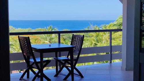 德赛Hotel - Résidence Habitation Grande Anse的阳台配有一张桌子和两把椅子,享有海景