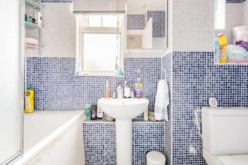 伦敦Lovely and comfortable Home Stay in London的蓝色瓷砖浴室设有水槽和浴缸