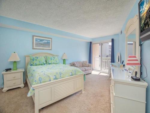 威尔伍德克拉斯特1B/1B condo with Ocean views, Resort style, Free WIFI, Few steps to the Beach!!的一间拥有蓝色墙壁的卧室、一张床和窗户