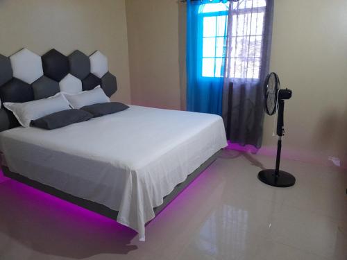 布莱克河Loodik Vacation Home Brompton Manor的一间卧室配有一张白色床和紫色灯