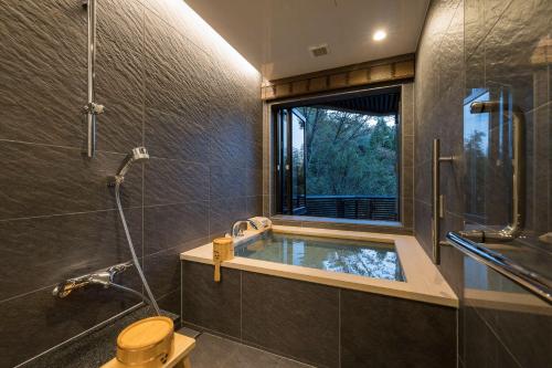 神户金山酒店的一间带浴缸和淋浴的浴室,并设有一个窗户