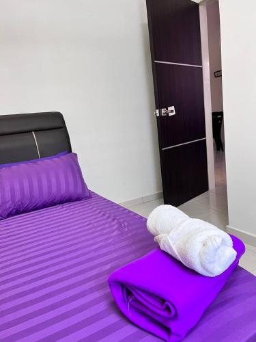 亚娄RAINA MUSLIM FRIENDLY HOMESTAY Perlis的一张带紫色床单和毛巾的床
