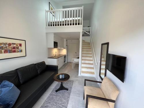 哈尔姆斯塔德Stugcentralen Lägenheter & Stugor的客厅设有黑色沙发和楼梯。