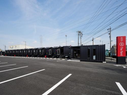 海津市HOTEL R9 The Yard Kaizu的一个空的停车场,有一排黑的容器