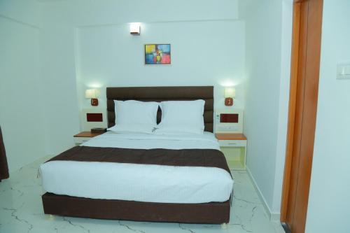 古鲁瓦尤尔Utsavam Hotel Apartments的一间卧室配有一张带白色床单的大床