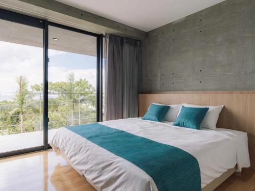 读谷村Bosco Yomitan Resort Condminium的一间卧室设有一张大床和一个大窗户