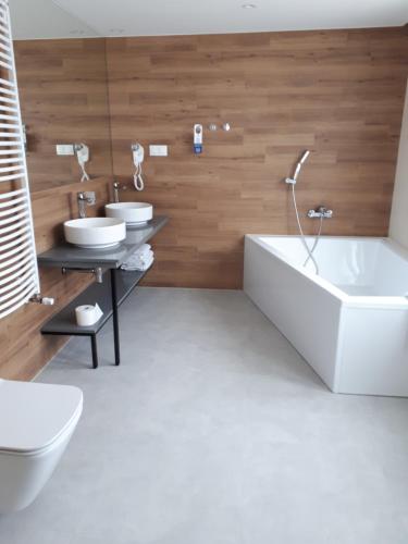 托伦Halo Toruń的一间带两个盥洗盆、浴缸和卫生间的浴室