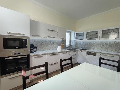 凯斯特海伊Zimmerferi Apartman Keszthely的厨房配有白色橱柜和桌椅
