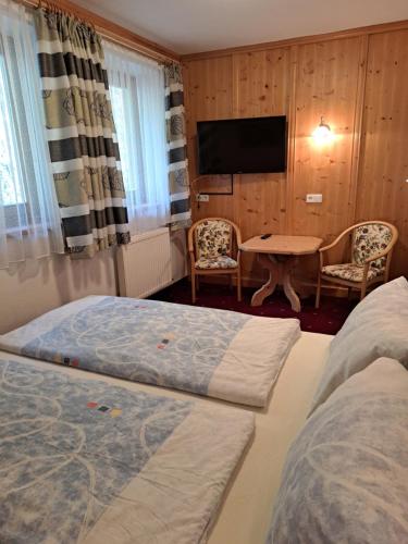 翁肯Berggasthof Hintergföll的一间酒店客房,设有两张床、一张桌子和一台电视机