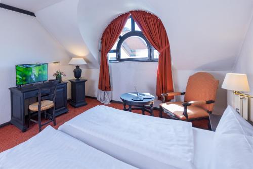 居特斯洛Hotel Stadt Gütersloh的一间卧室设有一张床、一台电视和一个窗口。