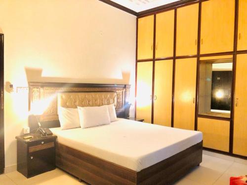 拉合尔Lotus One Hotel的一间卧室配有一张大床和一个带灯的床头柜
