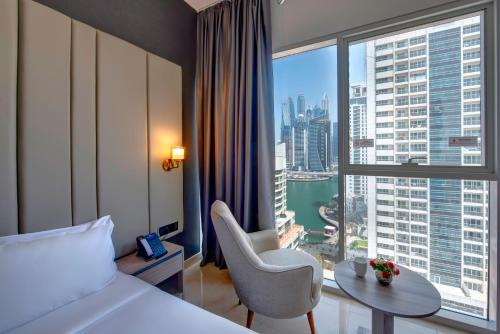 迪拜Royal Regency Suites Marina的酒店客房设有一张床铺、一张桌子和一个大窗户。