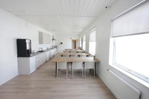 EiðarEiðar - Hostel的一间设有桌子的房间和一间带白色橱柜的厨房