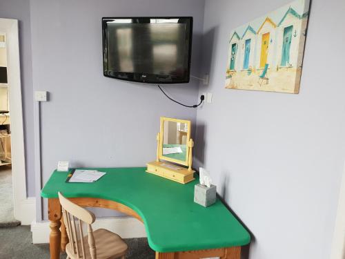 大雅茅斯亨利舞会酒店的一张带镜子的绿色书桌和墙上的电视
