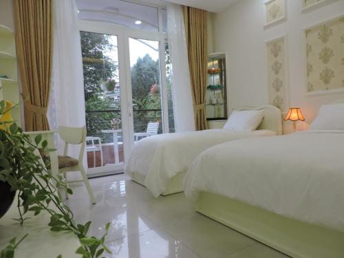 胡志明市Chez Lotus Rose的一间白色卧室,配有两张床和一个阳台