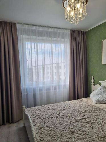 马热伊基艾Sodų skg. 10的一间卧室配有一张带吊灯和窗户的床。