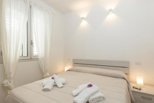圣玛丽亚纳瓦雷Melania Holidays Home - Sole Incantatore的白色卧室,配有带窗户的床上毛巾