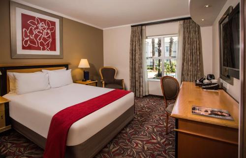 约翰内斯堡花苑晨桑顿酒店的配有一张床、一张书桌和一扇窗户的酒店客房