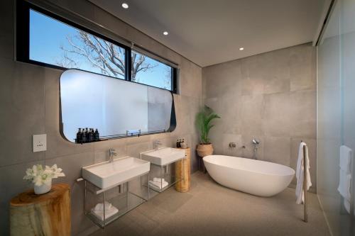 约翰内斯堡皮池酒店的一间带两个盥洗盆、浴缸和窗户的浴室