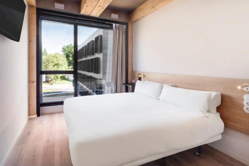 吉马良斯B&B HOTEL Guimarães的配有大窗户的客房内的白色床