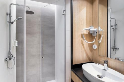 吉马良斯B&B HOTEL Guimarães的带淋浴、盥洗盆和镜子的浴室