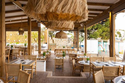 梅加利阿莫斯Skiathos Thalassa Cape, Philian Hotels and Resorts的餐厅设有桌椅和大窗户。