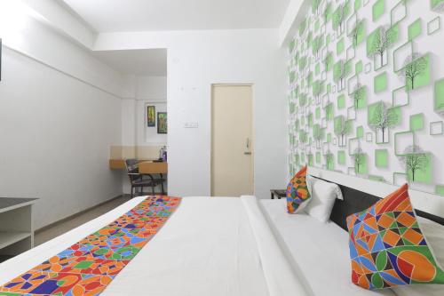 巴特那The Ashiyana Inn Hotel的卧室配有一张带彩色枕头的大型白色床。