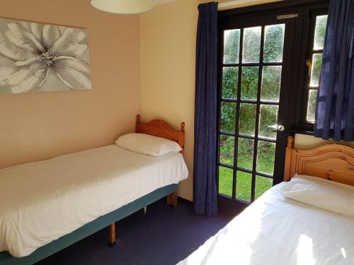海尔Tolroy Manor Holiday Park的一间卧室设有两张床和窗户。