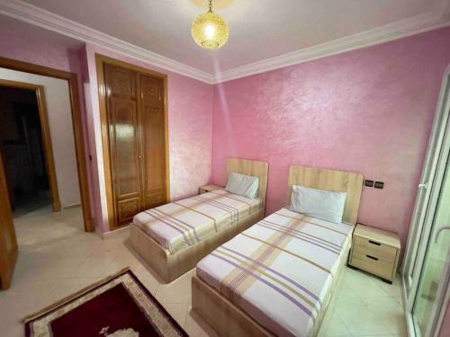 穆罕默迪耶Résidence Al Kawtar的配有粉红色墙壁的客房内的两张床