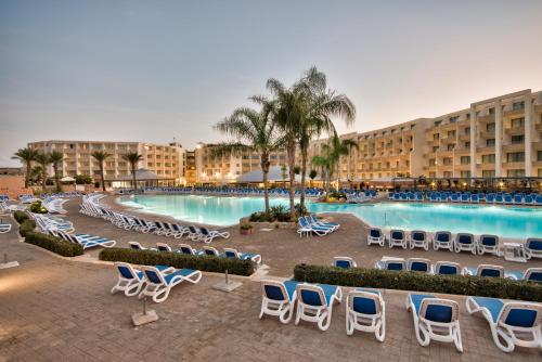 梅利哈db Seabank Resort + Spa All Inclusive的一个带游泳池、椅子和棕榈树的度假村