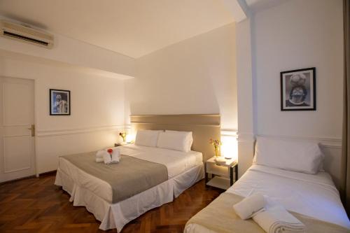 布宜诺斯艾利斯El Misti Hotel Buenos Aires Centro的配有白色墙壁和木地板的客房内的两张床