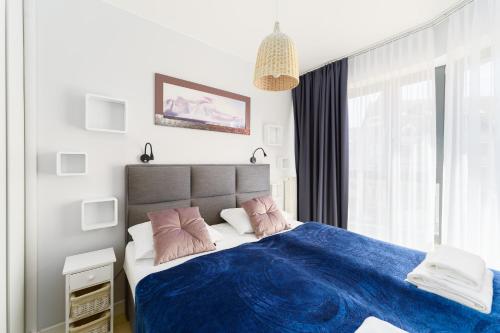 米兹多洛杰Horyzont Apartament z Klimatyzacją i Balkonem by Renters的一间卧室配有一张带蓝色床单和粉红色枕头的床。