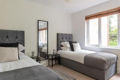 克劳利Bright, Modern, Fully Furnished Apartment - 2 FREE PARKING Spaces - 8 min LGW Airport的一间卧室配有两张床和镜子