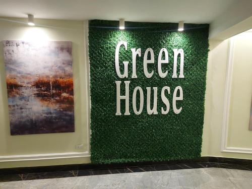 As SuwaysGreen House Hotel的墙上的绿色房屋标志