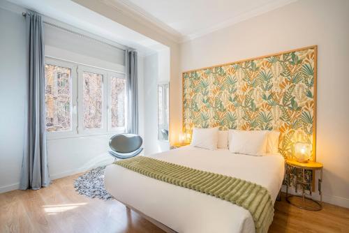 巴塞罗那巴塞罗那埃克萨潘区公寓的卧室配有一张床,墙上挂有绘画作品