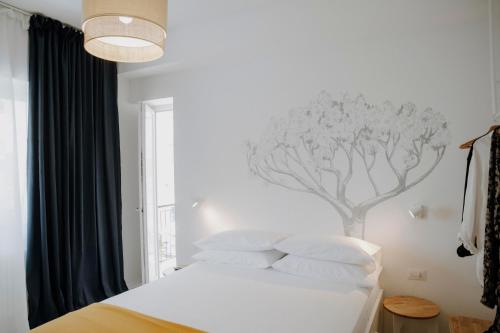 泰拉奇纳PETRARCA17 Guest house a due passi dal mare的卧室配有白色床,墙上挂有树壁画