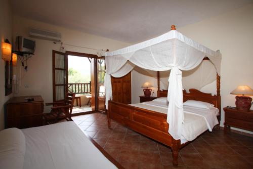 斯科派洛斯太阳住宿酒店的一间卧室设有一张天蓬床和一个阳台