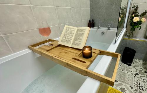 庞蒂浦Stylish & Cosy - Flat 6, Osborne Road的浴缸里坐着一本书和一杯葡萄酒