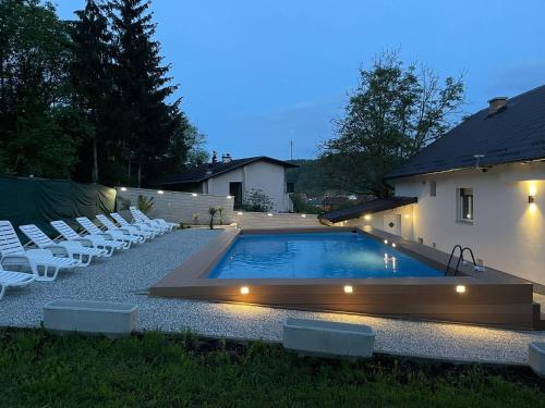 萨格勒布Vila s bazenom deluxe - GTI的一个带白色椅子的游泳池以及一座房子